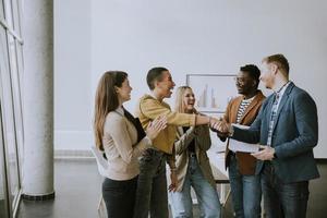 Memembers of creative team shaking hands while working in the modern office photo