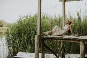 Relaxing young woman on wooden pier at the lake photo