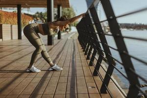 Young woman in sportswear exercising on a river promenade photo