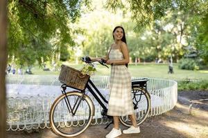 mujer joven con flores en la cesta de la bicicleta eléctrica foto