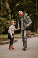 Grandfather spending time with his granddaughter in park on autumn day photo