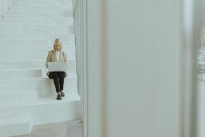 Businesswoman with laptop on modern office stairs photo