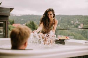 Young couple enjoying in outdoor hot tub on vacation photo