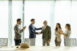 Business partners handshaking after making agreement with employees near by photo