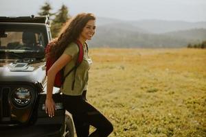 Young woman relaxing on a terrain vehicle hood at countryside photo