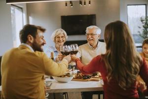 Happy family having dinner with red wine at home photo