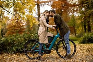 pareja joven, en, el, otoño, parque, con, bicicleta eléctrica foto