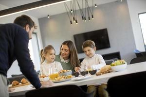 Young happy family talking while having breakfast at dining table photo