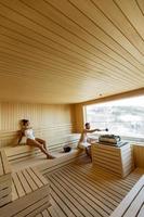 Young couple relaxing in the sauna and watching winter forest through the window photo