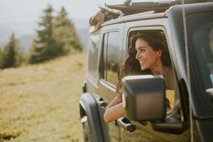 mujer joven que disfruta de la libertad en un vehículo todoterreno en un día soleado foto