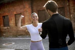 Young woman checking results after jogging with her personal trainer photo