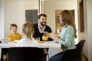 Young happy family talking while having breakfast at dining table photo