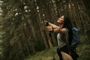 Young female backpacker woman enjoying green beautiful forest around her photo