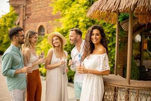 Group of young people cheering and having fun outdoors with drinks photo