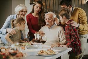 Family celebrating grandfather birthday with cake and candles at home photo