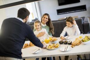 Young happy family talking while having breakfast at dining table photo