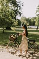 mujer joven con flores en la cesta de la bicicleta eléctrica foto