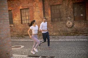 Young fitness couple running in urban area photo