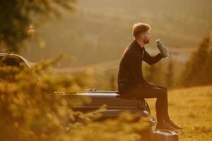 Young man relaxing on a terrain vehicle hood at countryside photo