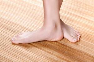 Beautiful female feet on a wooden floor, closeup shot photo