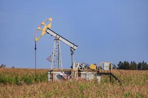 The old oil pump in a field under blue sky photo