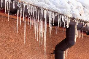 Winter icicles hanging from eaves of roof photo