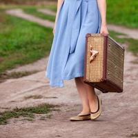 Pretty woman travels on the road in the field. Girl with with a big suitcase photo