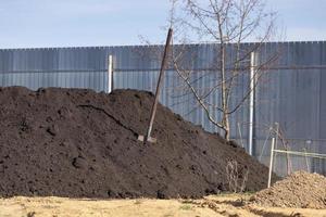 Heap of black soil and a spade in a garden photo