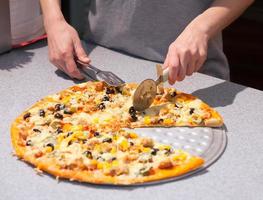 Chef cutting freshly baked pizza photo