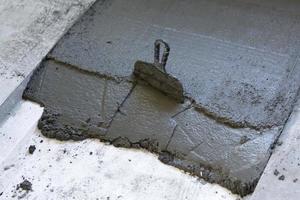 A trowel in a layer of fresh concrete on the floor photo