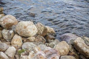 papel tapiz con piedras junto al río y el agua. dar un paseo por el parque en un día de verano y admirar el hermoso paisaje. enfoque selectivo, papel tapiz. foto