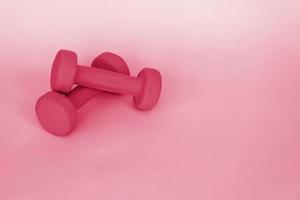 Green dumbbells for sports on a pink background. Sports, sports nutrition, healthy eating, diet. Space for the text. photo