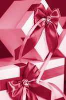 The gift box is white with a beautiful gray bow. Gift on a dark background. Holidays and surprises. Satin bows with rhinestones Viva Magenta Background color photo