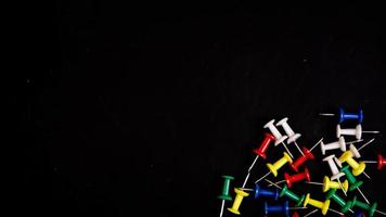 multicolored thumbtacks on a black background photo