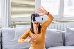Excited young woman wearing virtual reality glasses and screaming because of unbelievable effects in 3d digital world. Impressed lady yelling and gesturing when using VR technology for the first time photo