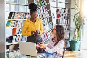 Working team is talking at desk with laptop in modern office. Two people discussing information seen on screen of silvery device and smiling friendly. Prospective staff dressed in formal clothes photo