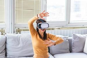 hermosa mujer tocando el aire durante la experiencia vr. bella mujer con gafas de realidad virtual en un hogar moderno. teléfono inteligente con auriculares vr. foto
