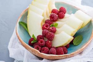Melon slices served with raspberry and honey photo