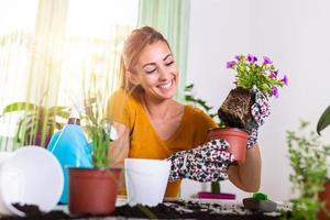 Lovely housewife with flower in pot and gardening set. Work at home. Planting a flower and spring cleaning. The housewife changes ground for a plant. Care for a potted plant photo