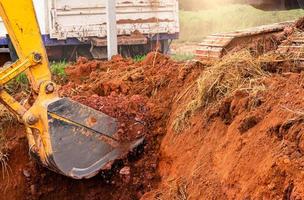 Excavator bucket digging soil for loading to truck. Earthwork. Dirt metal bucket of backhoe working at a construction site. Earthmoving machine. Earth excavation. Excavator digging on demolition site. photo