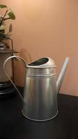 Galvanize silver watering can at the table for plant watering at home garden. photo