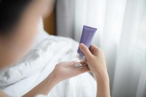 Close up of women applying body lotion cream on hand. photo