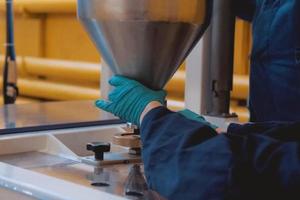 worker at the plant holds a funnel with a filler. photo