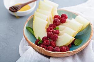 Melon slices served with raspberry and honey photo