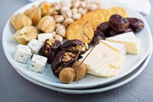 Cheese plate with crackers, dates and nuts photo