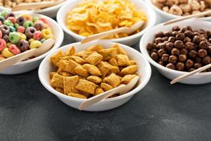 Variety of cold cereals in white bowls with spoons photo