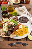 Beef kebab with rice, beans and fried plantains photo