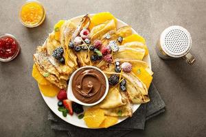 Thin crepes with fresh fruit and berries photo