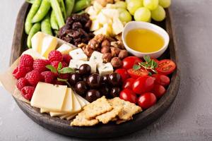 plato de queso con verduras y frutas frescas foto