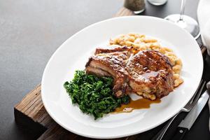 Grilled pork chop with cassoulet and braised greens photo